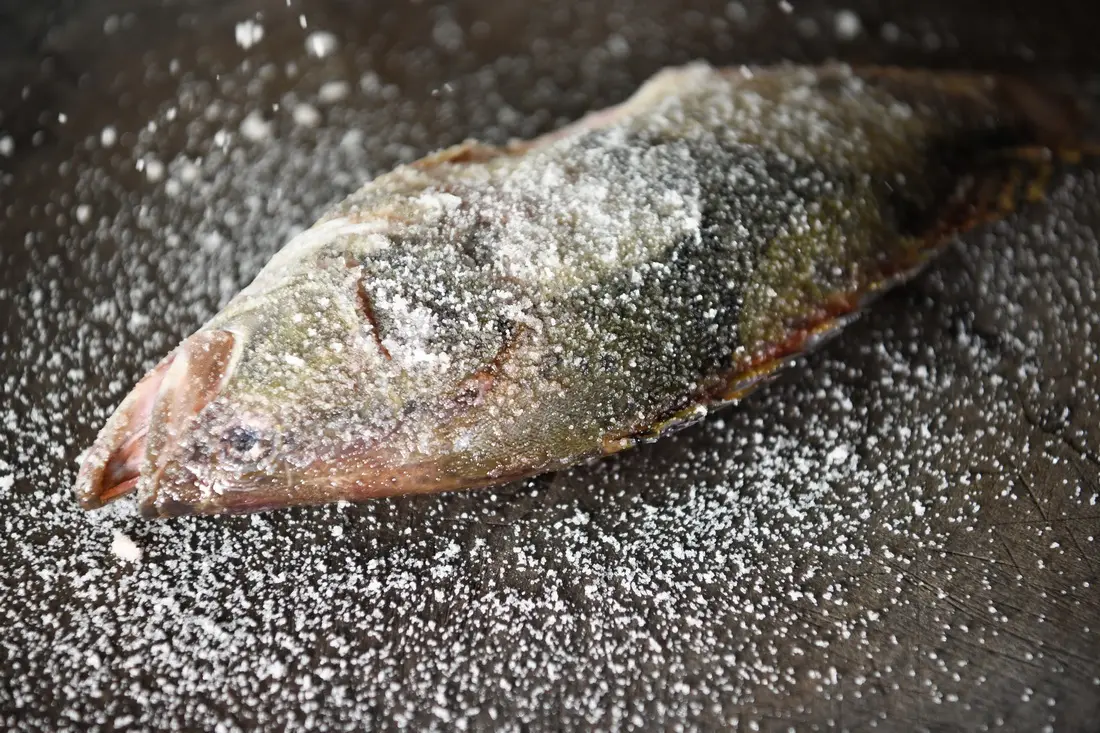 Raw stinky mandarin fish on a cutting board, salt-packed and ready for fermentation