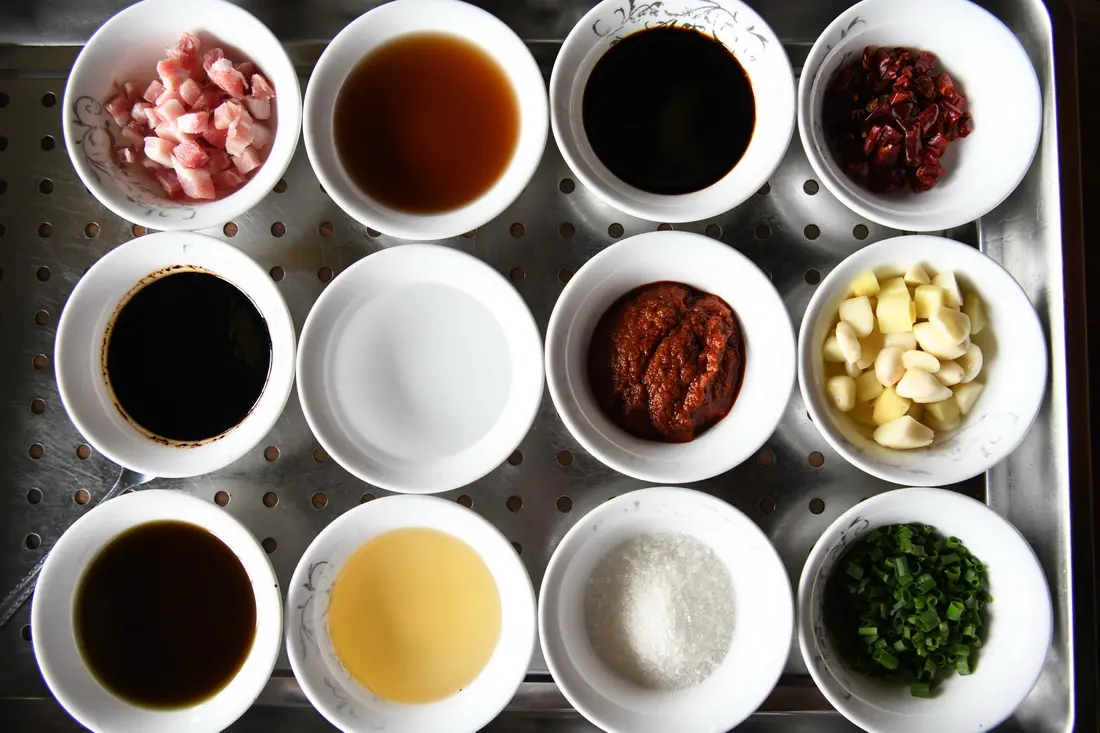 Twelve small bowls of seasonings arranged for cooking stinky mandarin fish