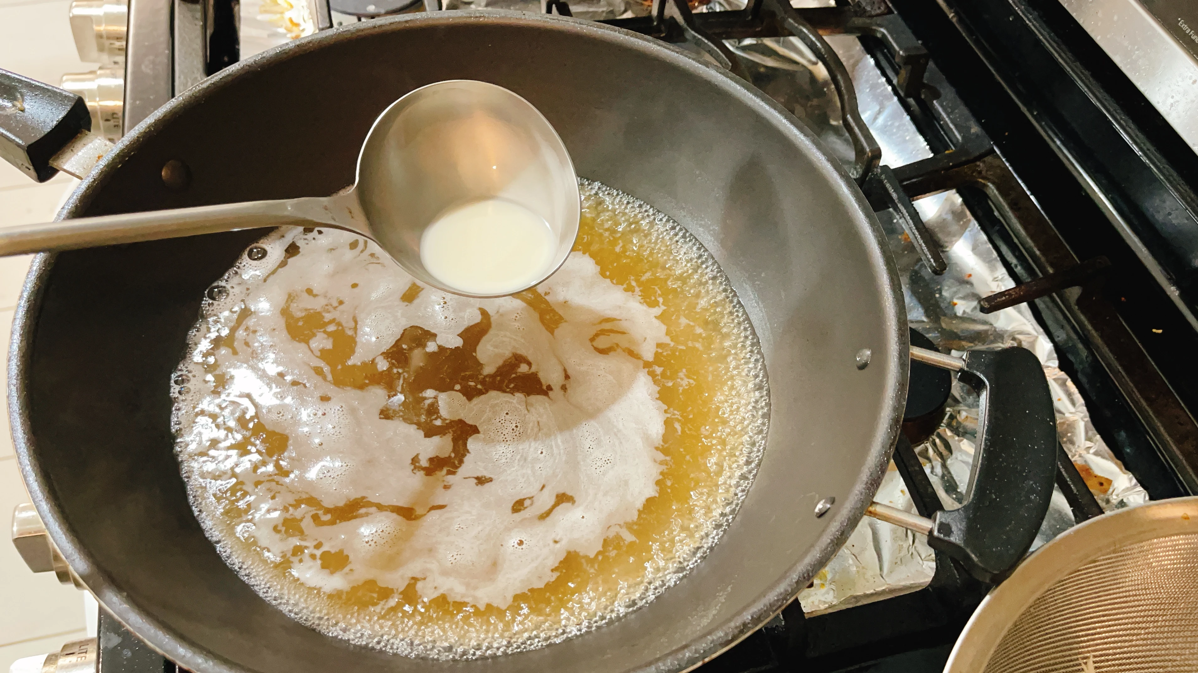 A starch slurry being stirred into a wok to thicken the sauce